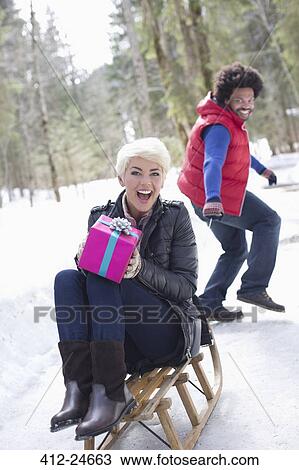 Man pulling woman with gift on sled in snow View Large Photo Image Stock Image - Man pulling woman with gift on sled in snow. Fotosearch