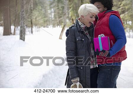 Man surprising woman with gift in snow View Large Photo Image Stock Image - Man surprising woman with gift in snow. Fotosearch