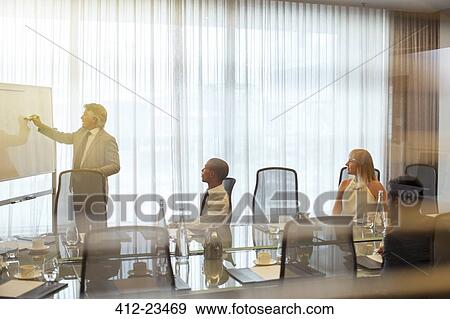 Stock Photo - Mature businessman giving presentation to colleagues in conference room. Fotosearch