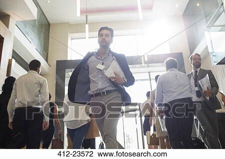 Stock Image - Men holding documents and running in office corridor. Fotosearch
