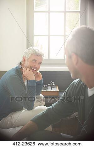 Men relaxing together in living room View Large Photo Image Stock Photograph - Men relaxing together in living room. Fotosearch