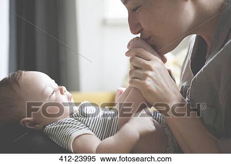 Stock Photography - Mother holding and kissing little baby's feet. Fotosearch
