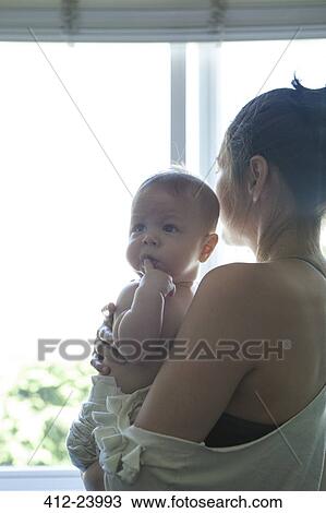Mother holding little baby and looking through window View Large Photo Image Stock Image - Mother holding little baby and looking through window . Fotosearch
