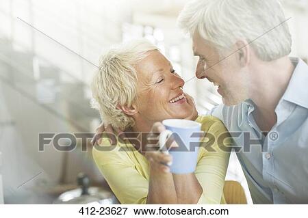 Stock Photo - Older couple hugging with coffee cup. Fotosearch