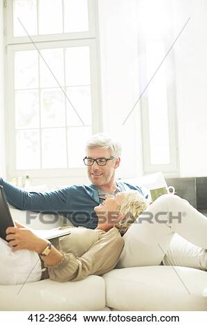 Older couple relaxing together on living room sofa View Large Photo Image Picture - Older couple relaxing together on living room sofa. Fotosearch