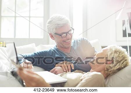 Stock Photo - Older couple relaxing together on sofa. Fotosearch