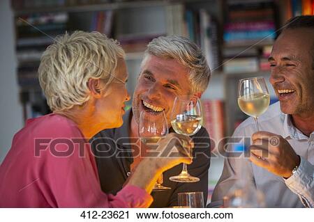 Stock Image - Older friends drinking wine. Fotosearch