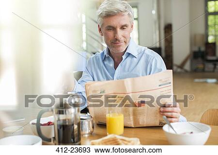 Older man reading newspaper at breakfast table View Large Photo Image Stock Image - Older man reading newspaper at breakfast table. Fotosearch