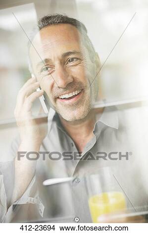 Older man talking on cell phone at breakfast View Large Photo Image Picture - Older man talking on cell phone at breakfast. Fotosearch