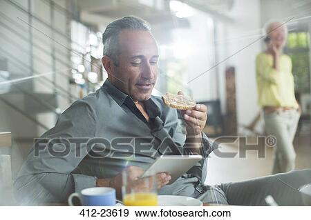 Stock Photo - Older man using digital tablet at breakfast table. Fotosearch