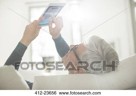 Older man using digital tablet in living room View Large Photo Image Stock Photograph - Older man using digital tablet in living room. Fotosearch
