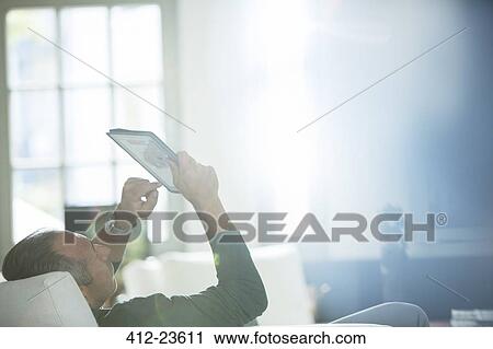 Older man using digital tablet on sofa View Large Photo Image Stock Image - Older man using digital tablet on sofa. Fotosearch