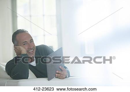 Older man using digital tablet on sofa View Large Photo Image Stock Image - Older man using digital tablet on sofa. Fotosearch