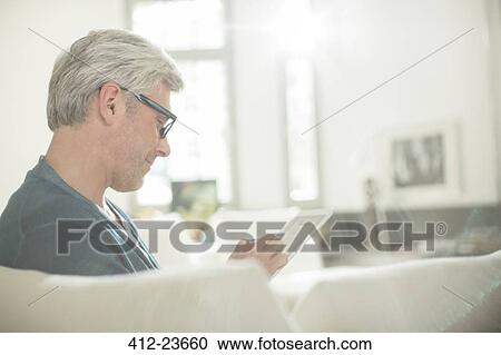 Older man using digital tablet on sofa View Large Photo Image Stock Image - Older man using digital tablet on sofa. Fotosearch