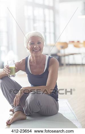 Older woman drinking juice on exercise mat View Large Photo Image Picture - Older woman drinking juice on exercise mat. Fotosearch