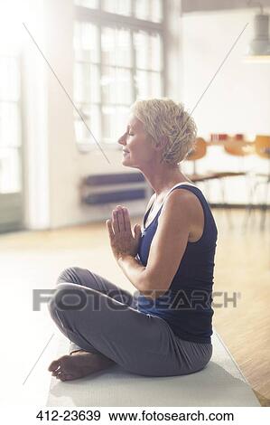 Stock Photo - Older woman meditating on exercise mat. Fotosearch