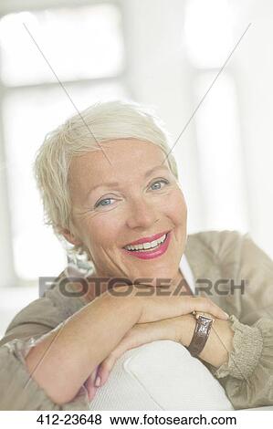 Stock Photo - Older woman smiling on sofa. Fotosearch