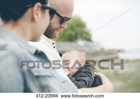 Parents wearing sunglasses holding little baby outdoors View Large Photo Image Picture - Parents wearing sunglasses holding little baby outdoors. Fotosearch