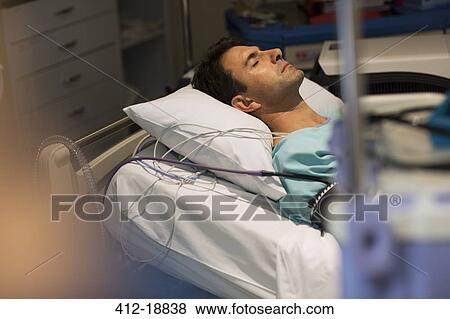 Patient attached to medical monitoring equipment lying in bed in intensive care unit View Large Photo Image Stock Photo - Patient attached to medical monitoring equipment lying in bed in intensive care unit. Fotosearch