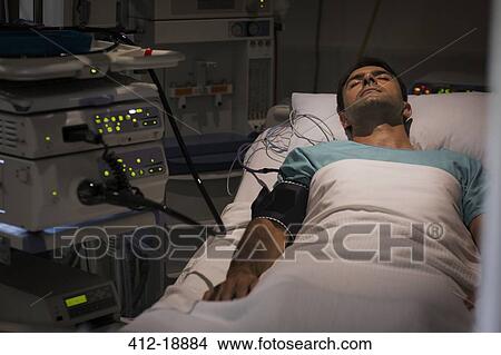 Patient lying in bed, attached to monitoring equipment in intensive care unit View Large Photo Image Picture - Patient lying in bed, attached to monitoring equipment in intensive care unit. Fotosearch