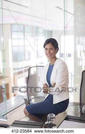 Portrait of beautiful smiling businesswoman sitting at glass table in conference room View Large Photo Image Picture - Portrait of beautiful smiling businesswoman sitting at glass table in conference room. Fotosearch