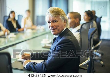 Portrait of businessman sitting at conference table in conference room View Large Photo Image Stock Photography - Portrait of businessman sitting at conference table in conference room. Fotosearch