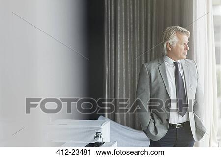 Portrait of businessman with hands in pockets standing in conference room, looking out of window View Large Photo Image Stock Image - Portrait of businessman with hands in pockets standing in conference room, looking out of window. Fotosearch
