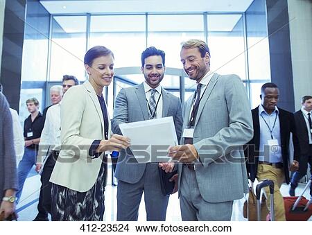 Picture - Portrait of businesswoman and two businessmen standing in lobby of conference center. Fotosearch
