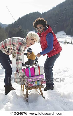 Portrait of couple with sled and Christmas gifts in snow View Large Photo Image Stock Photograph - Portrait of couple with sled and Christmas gifts in snow. Fotosearch