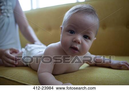 Portrait of little baby lying on front on yellow sofa, looking at camera View Large Photo Image Picture - Portrait of little baby lying on front on yellow sofa, looking at camera. Fotosearch
