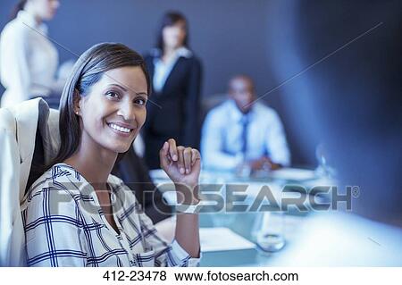 Portrait of mid adult businesswoman sitting in conference room and looking away View Large Photo Image Stock Photo - Portrait of mid adult businesswoman sitting in conference room and looking away. Fotosearch