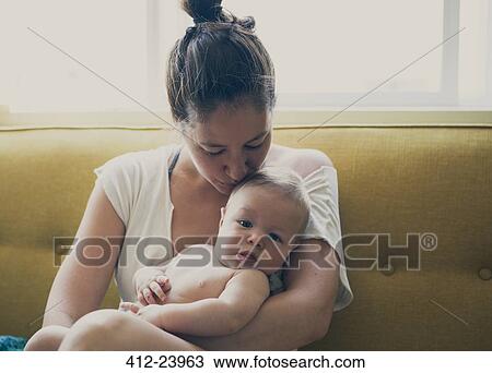 Portrait of mother holding and kissing baby, sitting on sofa by window View Large Photo Image Stock Image - Portrait of mother holding and kissing baby, sitting on sofa by window. Fotosearch
