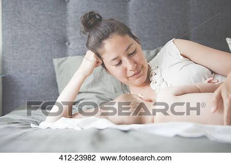 Portrait of mother holding baby lying on bed and smiling View Large Photo Image Stock Image - Portrait of mother holding baby lying on bed and smiling. Fotosearch