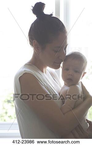 Portrait of mother holding baby, standing beside window with eyes closed View Large Photo Image Stock Photograph - Portrait of mother holding baby, standing beside window with eyes closed. Fotosearch