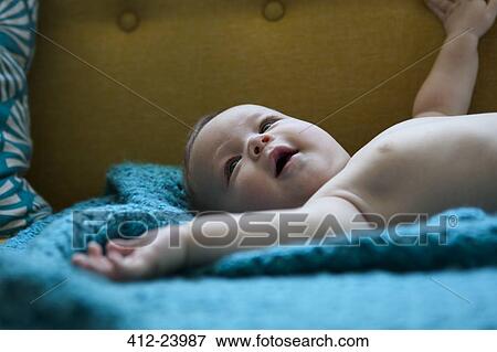 Stock Photo - Portrait of smiling baby lying on blue cloth with arms outstretched. Fotosearch