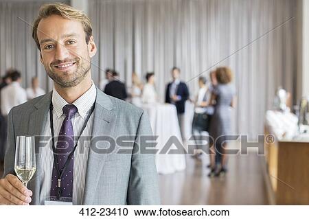 Stock Image - Portrait of smiling businessman holding champagne flute. Fotosearch