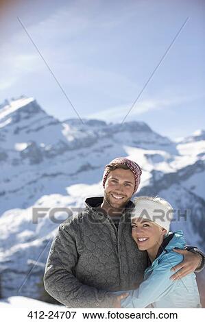 Portrait of smiling couple hugging below mountain View Large Photo Image Stock Photo - Portrait of smiling couple hugging below mountain. Fotosearch
