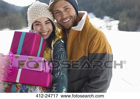 Portrait of smiling couple with Christmas gifts in snow View Large Photo Image Stock Photo - Portrait of smiling couple with Christmas gifts in snow. Fotosearch
