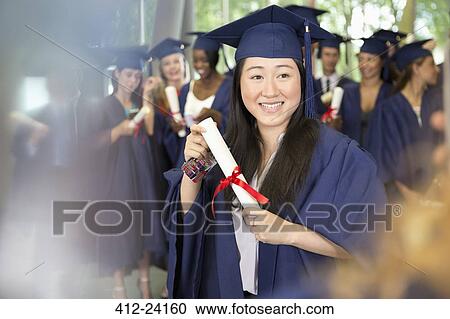 Portrait of smiling female student in graduation gown holding diploma View Large Photo Image Stock Image - Portrait of smiling female student in graduation gown holding diploma. Fotosearch