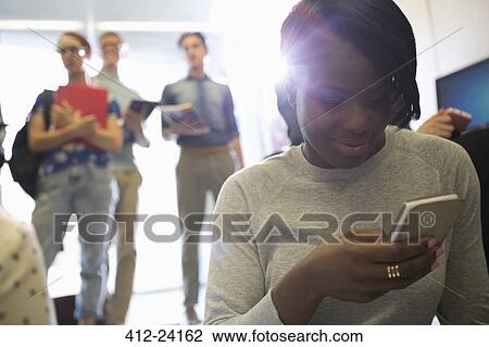 Portrait of smiling female student looking at smart phone with other students in background View Large Photo Image Stock Image - Portrait of smiling female student looking at smart phone with other students in background. Fotosearch