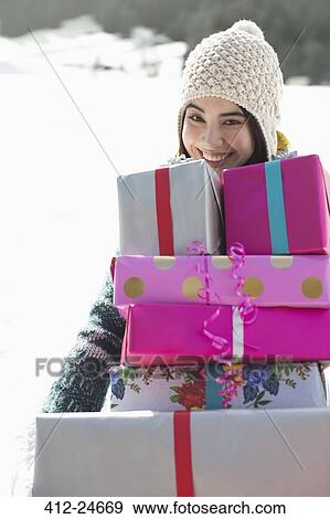 Portrait of smiling woman carrying stack of gifts View Large Photo Image Stock Photo - Portrait of smiling woman carrying stack of gifts. Fotosearch