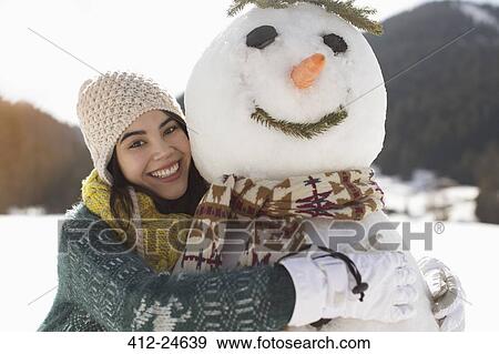 Portrait of smiling woman hugging snowman View Large Photo Image Stock Photo - Portrait of smiling woman hugging snowman. Fotosearch