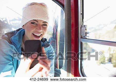 Stock Photo - Portrait of smiling woman taking selfie in ski lift. Fotosearch