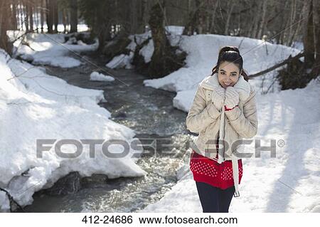 Stock Photograph - Portrait of smiling woman walking along snowy riverbank. Fotosearch