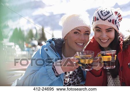 Stock Photography - Portrait of smiling women in warm clothing drinking tea outdoors. Fotosearch