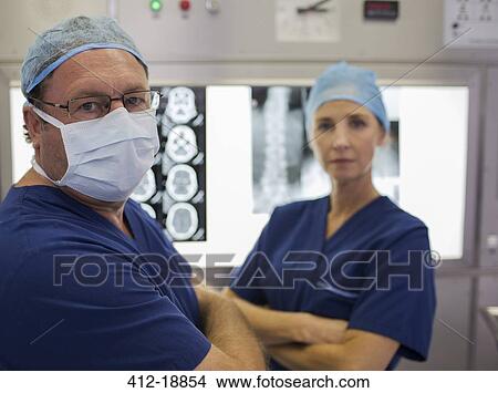 Portrait of surgeons with arms crossed, standing in front of MRI scan and x-ray View Large Photo Image Picture - Portrait of surgeons with arms crossed, standing in front of MRI scan and x-ray. Fotosearch