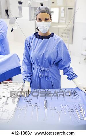 Portrait of surgical nurse standing behind medical tools on table in operating theater View Large Photo Image Stock Photo - Portrait of surgical nurse standing behind medical tools on table in operating theater. Fotosearch