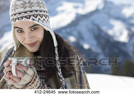 Stock Photography - Portrait of woman drinking hot cocoa in snow. Fotosearch