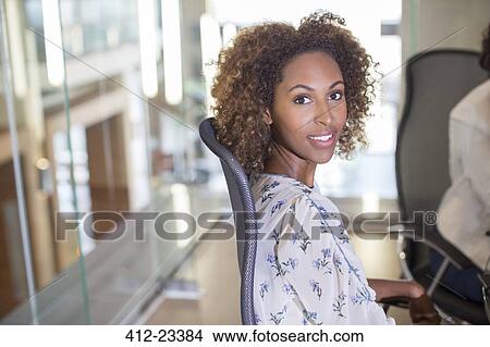 Portrait of young businesswoman sitting in chair and looking at camera View Large Photo Image Picture - Portrait of young businesswoman sitting in chair and looking at camera. Fotosearch