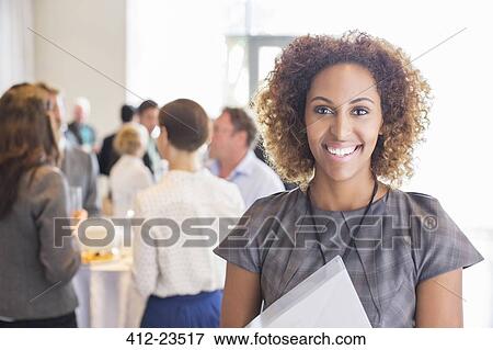 Portrait of young businesswoman standing and smiling in office hall View Large Photo Image Stock Photo - Portrait of young businesswoman standing and smiling in office hall. Fotosearch